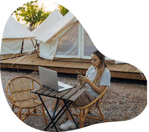 Woman using phone and laptop outdoors.